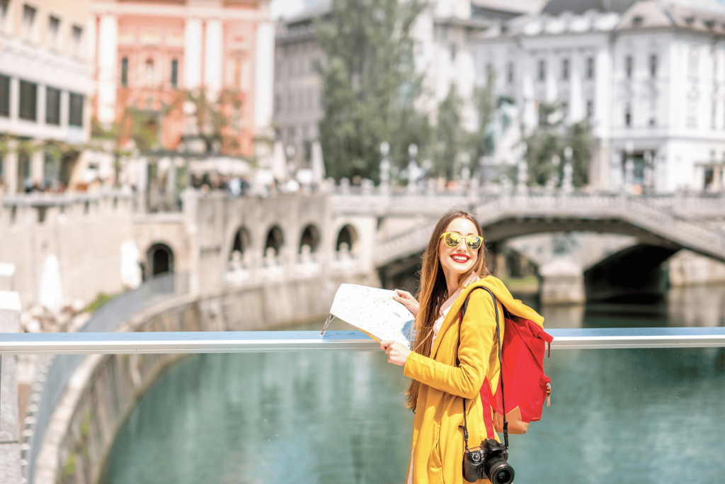 Woman in a yellow jacket and red lipstick in Slovenia. She is holding a map because she solo female travel