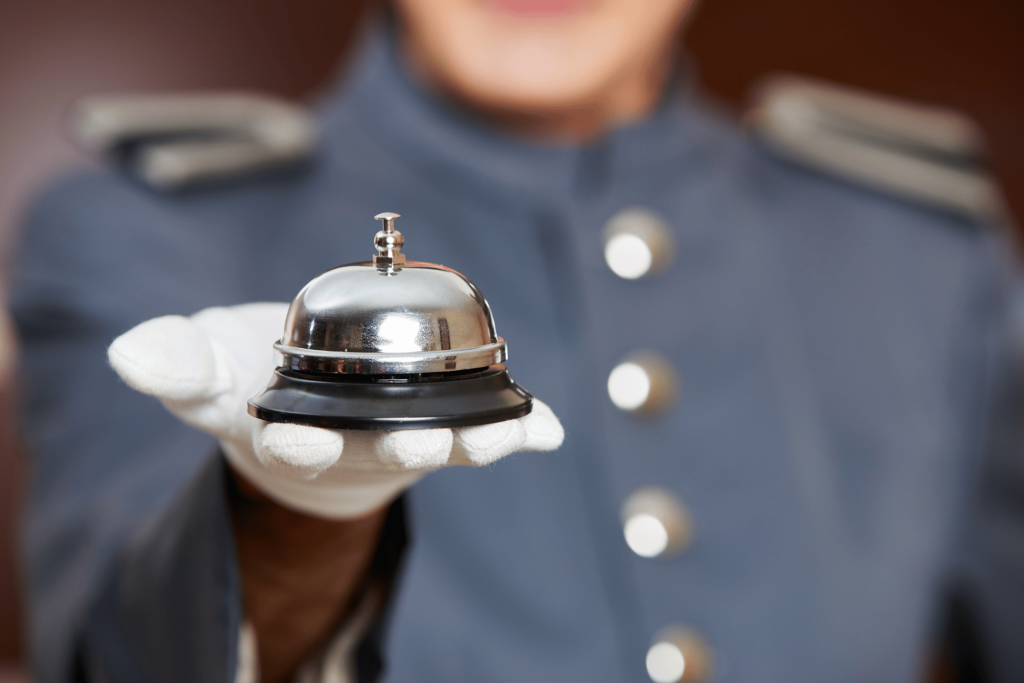 A concierge holding a bell. Hotels Travel Tweaks - make sure to download Tengah to save money for your five star luxury stay